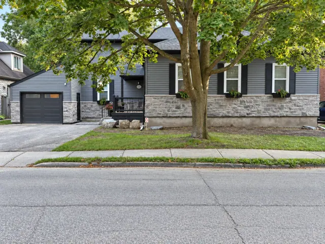 Stone facing across a grey house and attached garage, shaded by a front-yard tree